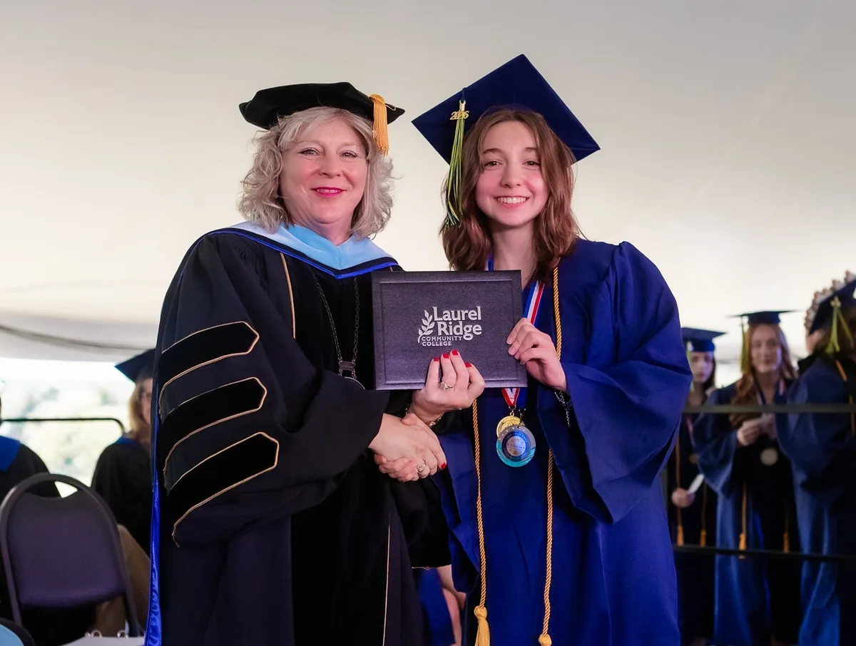 Two people in academic regalia holding a Laurel Ridge diploma at graduation