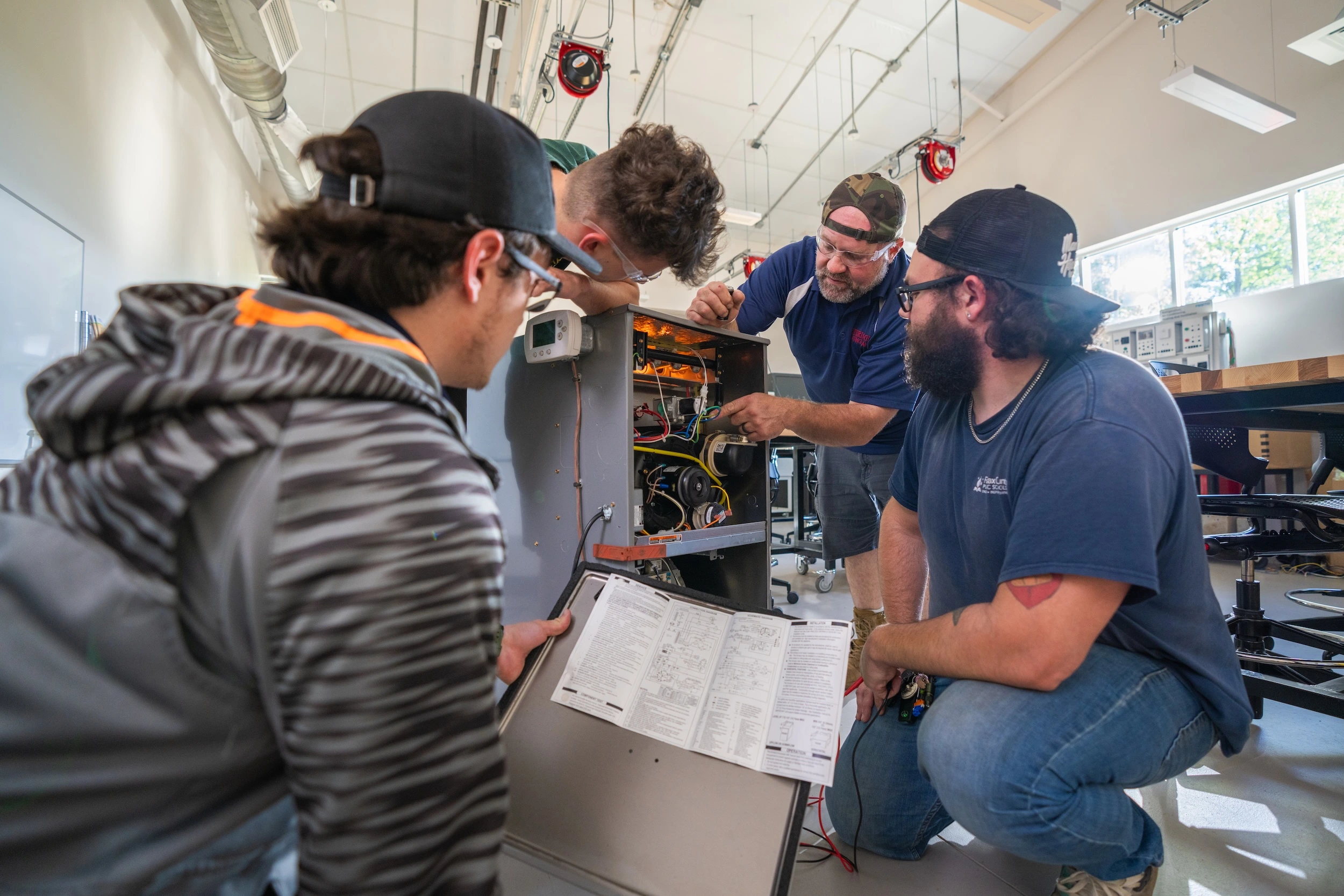Instructor and students gathered around open electrical equipment in a Laurel Ridge training lab